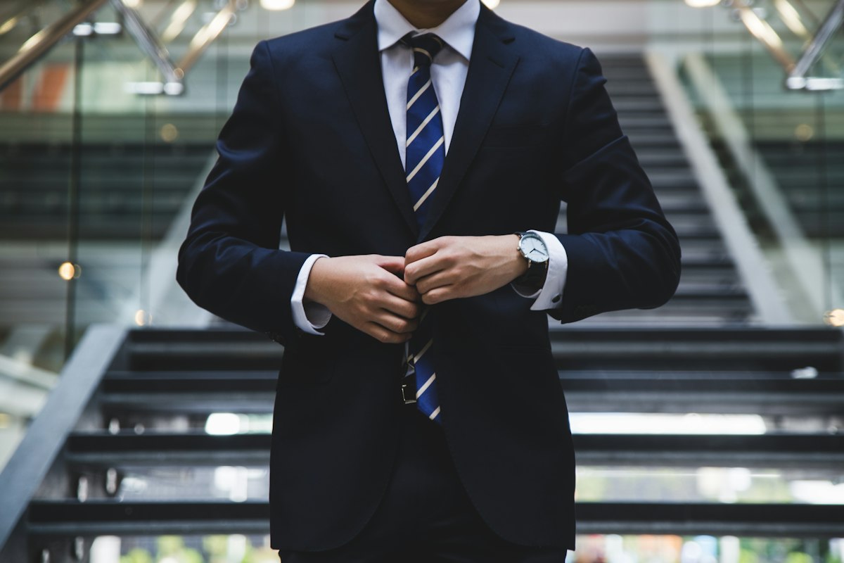Man in a navy suit buttoning his jacket