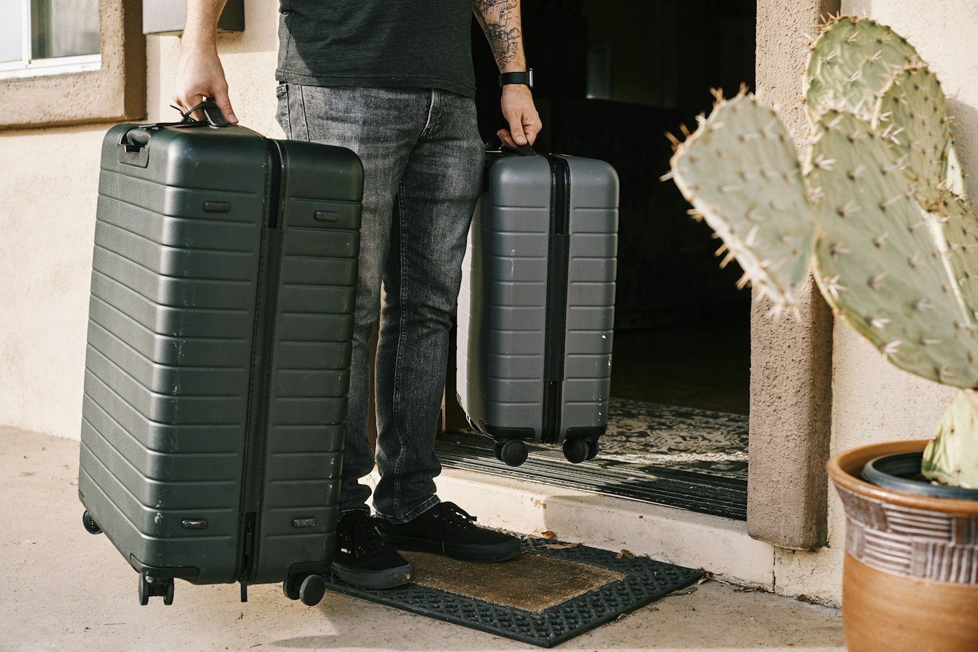 Two hard-shell suitcases beside a traveller