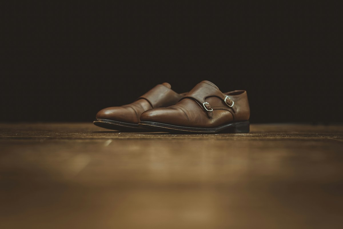 Brown double monk-strap shoes on a wooden floor